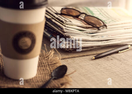 Quotidiani e tazze da caffè su tavole di legno. Foto Stock