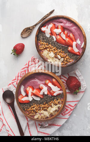 Colazione vegana concetto. Strawberry smoothies ciotola con le mandorle, chia, germogli e noce di cocco. Foto Stock