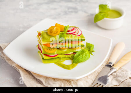 Materie zucchine lasagne con verdure e pesto, sfondo luminoso. Vegetariano crudo concetto di dieta. Foto Stock