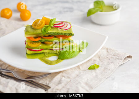 Materie zucchine lasagne con verdure e pesto, sfondo luminoso. Vegetariano crudo concetto di dieta. Foto Stock