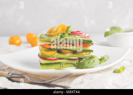 Materie zucchine lasagne con verdure e pesto, sfondo luminoso. Vegetariano crudo concetto di dieta. Foto Stock