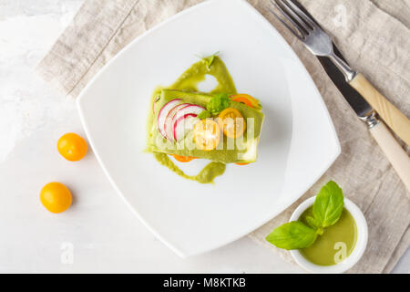 Materie zucchine lasagne con verdure e pesto, sfondo luminoso. Vegetariano crudo concetto di dieta. Foto Stock
