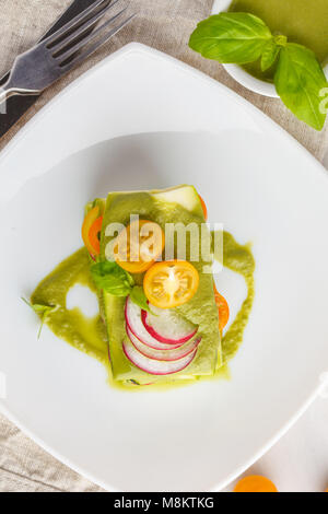 Materie zucchine lasagne con verdure e pesto, sfondo luminoso. Vegetariano crudo concetto di dieta. Foto Stock