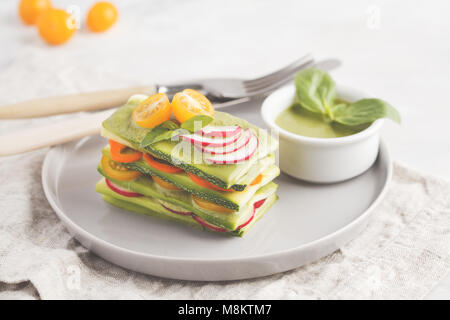 Materie zucchine lasagne con verdure e pesto, sfondo luminoso. Vegetariano crudo concetto di dieta. Foto Stock