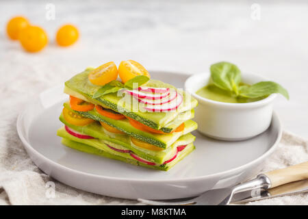 Materie zucchine lasagne con verdure e pesto, sfondo luminoso. Vegetariano crudo concetto di dieta. Foto Stock