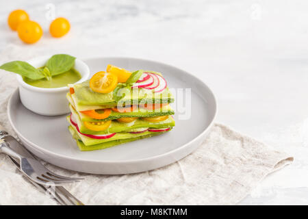 Materie zucchine lasagne con verdure e pesto, sfondo luminoso. Vegetariano crudo concetto di dieta. Foto Stock