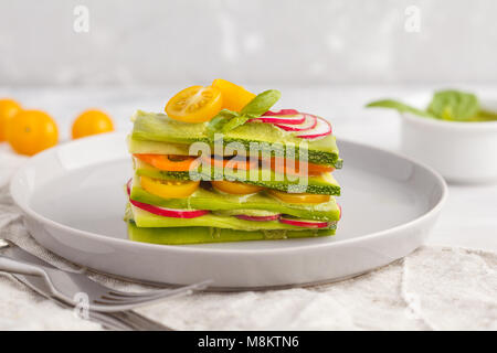 Materie zucchine lasagne con verdure e pesto, sfondo luminoso. Vegetariano crudo concetto di dieta. Foto Stock
