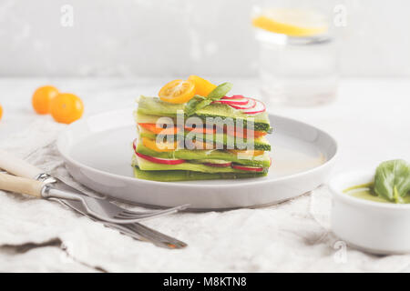 Materie zucchine lasagne con verdure e pesto, sfondo luminoso. Vegetariano crudo concetto di dieta. Foto Stock