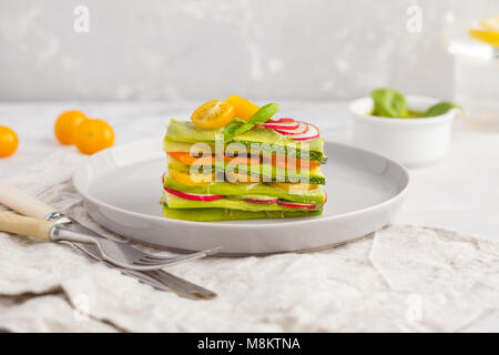 Materie zucchine lasagne con verdure e pesto, sfondo luminoso. Vegetariano crudo concetto di dieta. Foto Stock