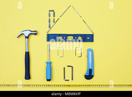 Selezione di strumenti a forma di casa home improvement concetto su sfondo giallo. Foto Stock