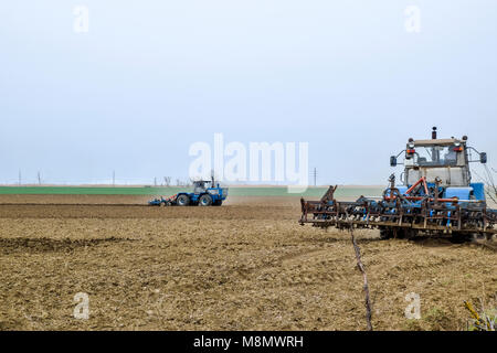Rigogliosa e allentare il suolo sul campo prima della semina. Il trattore aratri un campo con un aratro Foto Stock