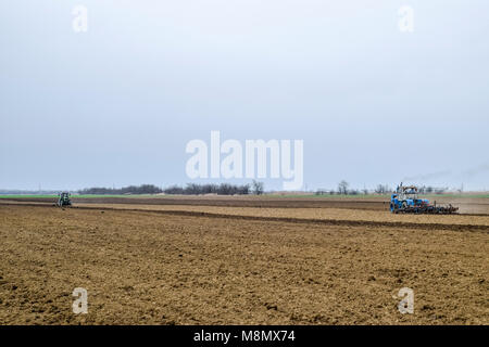 Rigogliosa e allentare il suolo sul campo prima della semina. Il trattore aratri un campo con un aratro Foto Stock