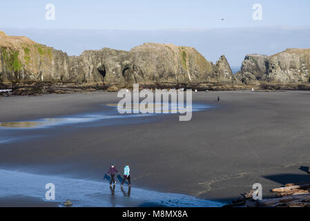 Persone che passeggiano sulla spiaggia nei pressi di affioramenti di roccia di Oregon Coast. Bandon, Oregon Foto Stock