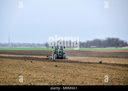 Rigogliosa e allentare il suolo sul campo prima della semina. Il trattore aratri un campo con un aratro Foto Stock