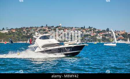 Power cruiser accelerando attraverso il Sydney Harbour contro lo sfondo dell'Harbourside sobborgo di Vaucluse, Nuovo Galles del Sud, Australia Foto Stock