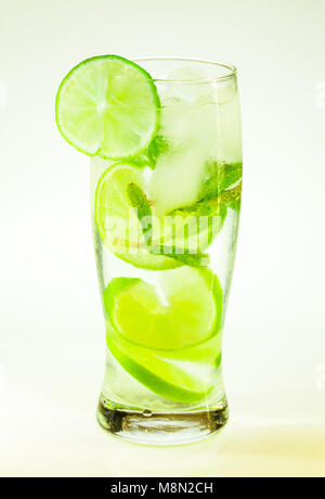 Estate bevanda fredda mojito lime e menta con ghiaccio e soda con gocce su un vetro su uno sfondo bianco Foto Stock