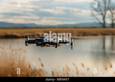 Piccolo e moderno drone di scattare una foto del lago al tramonto. Foto Stock