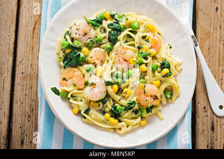 Re cremosa di gamberi tagliatelle con piselli, spinaci e il granturco dolce Foto Stock