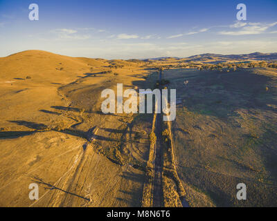 Dritta strada rurale passando attraverso la campagna australiana al tramonto Foto Stock