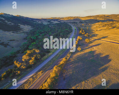 Vista aerea di Hume Highway passando attraverso la splendida campagna con ombre lunghe da alberi al tramonto in Australia Foto Stock