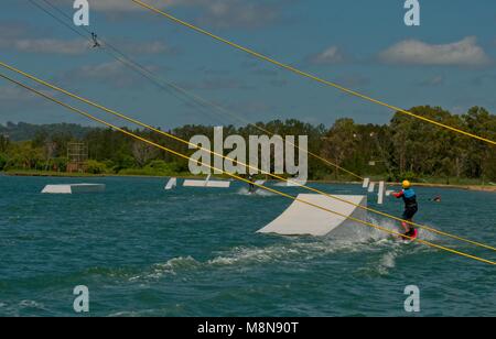 Bli Bli, Qld, Australia - 17 Marzo 2018: giovane adolescente di sesso maschile a cavallo di un Wakeboard a un cavo parco acquatico Foto Stock