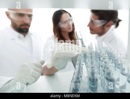 Immagine di sfondo è un gruppo di scienziati che studiano il liquido nel tubo di vetro. Foto Stock