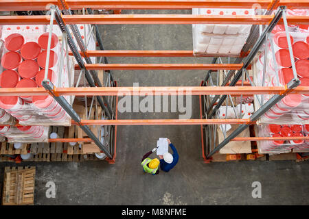 Vista dall'alto dell'immagine di sfondo del ripiano alti filari in magazzino moderno con due persone che indossano hardhats in piedi nella corsia Foto Stock