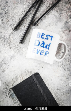 La Festa del Papà concetto, sfondo per congratularmi con le schede con una tazza con la scritta Best padre mai, business notebook e matite. spazio copia Foto Stock
