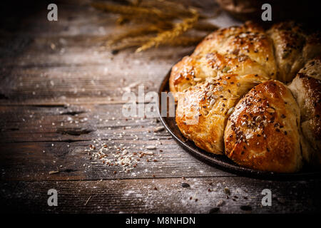 Triangolo di gustosi panini con semi su forno-tray, su sfondo di legno Foto Stock