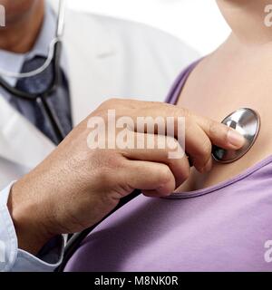 Medico utilizzando uno stetoscopio per esaminare la donna. Foto Stock