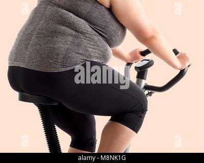 Donna sovrappeso sulla cyclette. Foto Stock