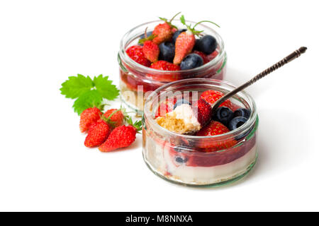 Mini wild frutti di bosco cheesecake in vasi di vetro isolato su sfondo bianco Foto Stock
