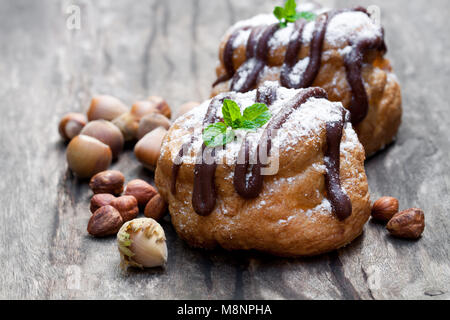 Il cioccolato belga choux panini farciti con crema alla nocciola sulla tavola di legno Foto Stock