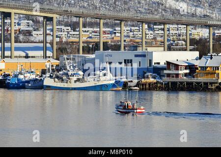 Piccolo rosso e bianco vascello sulla Tromsøysund con una vista a Tromsø bridge e altre navi in riva al mare, 6 Marzo 2017 | Utilizzo di tutto il mondo Foto Stock