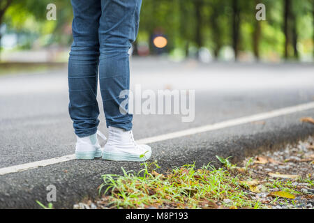 Chiudere il piede della donna backpacker permanente sulla strada di campagna con albero in verde primavera,stagionali da soli o di viaggio viaggiatore singolo concetto. Foto Stock