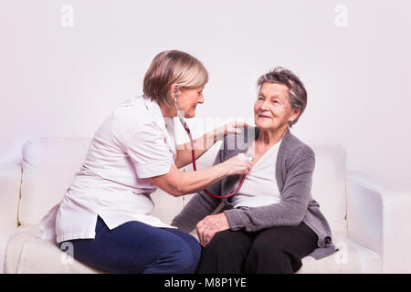 Ritratto in studio di un senior nurse esaminando una donna anziana. Foto Stock