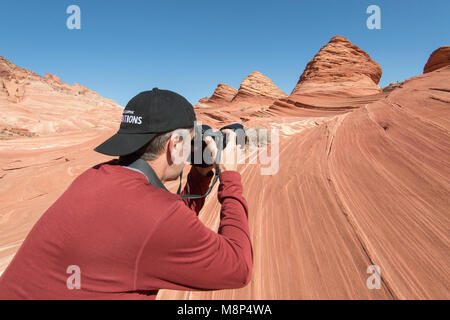 Un uomo prende una foto di forma piramidale formazioni arenarie in Coyote Buttes North. Foto Stock