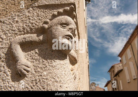 Muratura di pietra in Saint-Lizier, Occitanie, Francia: un volto scolpito in pietra sul angolo di due case storiche nel centro storico. Foto Stock