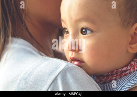 Carino asiatiche faccia bambino nelle braccia della madre Foto Stock