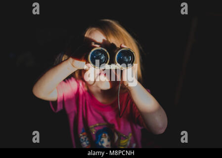 Una giovane ragazza toddler guardando attraverso il binocolo. Foto Stock