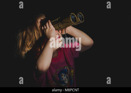 Una giovane ragazza toddler guardando attraverso il binocolo. Foto Stock