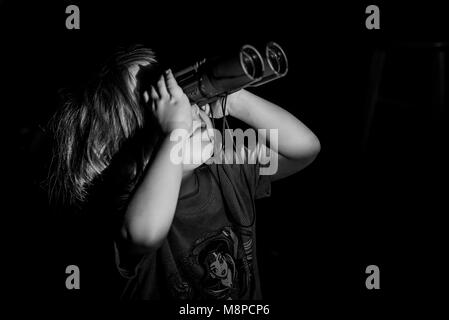 Una giovane ragazza toddler guardando attraverso il binocolo. Foto Stock