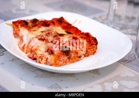 Vista ravvicinata di una porzione di lasagne servita su una piastra bianca Foto Stock