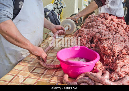 Il macellaio rende salsicce fatte in casa all'aperto in un modo tradizionale. Foto Stock