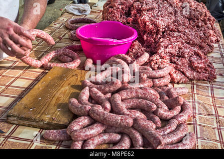 Il macellaio rende salsicce fatte in casa all'aperto in un modo tradizionale. Foto Stock