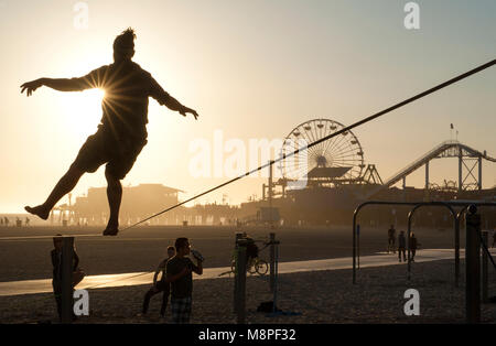 Man praticando sulla corda in spiaggia vicino al molo di Santa Monica, Los Angeles, CA Foto Stock