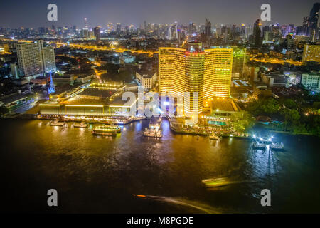 Panoramica vista aerea attraverso il Fiume Chao Phraya il Royal Orchid Sheraton Hotel e di edifici ad alta del centro cittadino e illuminata di notte Foto Stock