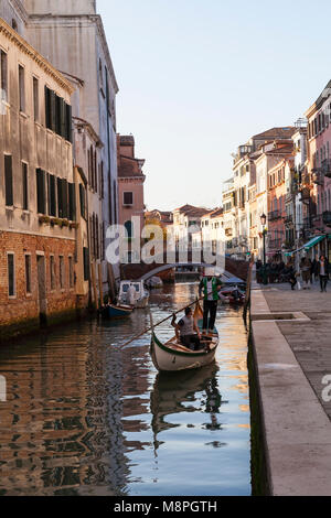 Il canottaggio una gondola su un tranquillo canale, Rio della Misericordia, in Cannaregio al tramonto, Venezia, Veneto, Italia al fianco di fondamenta Ormisini Foto Stock