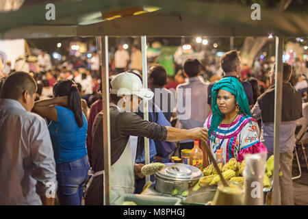 Oaxaca Oax., Messico - un alimento distributore vende il mais dal suo carrello nello Zocalo (piazza centrale) a notte. Foto Stock