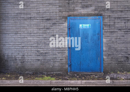 Tenere sgombra l'uscita di emergenza porta in fabbrica per la salute e la sicurezza dei lavoratori blu grigio e rosso plain Sfondo mattone Foto Stock